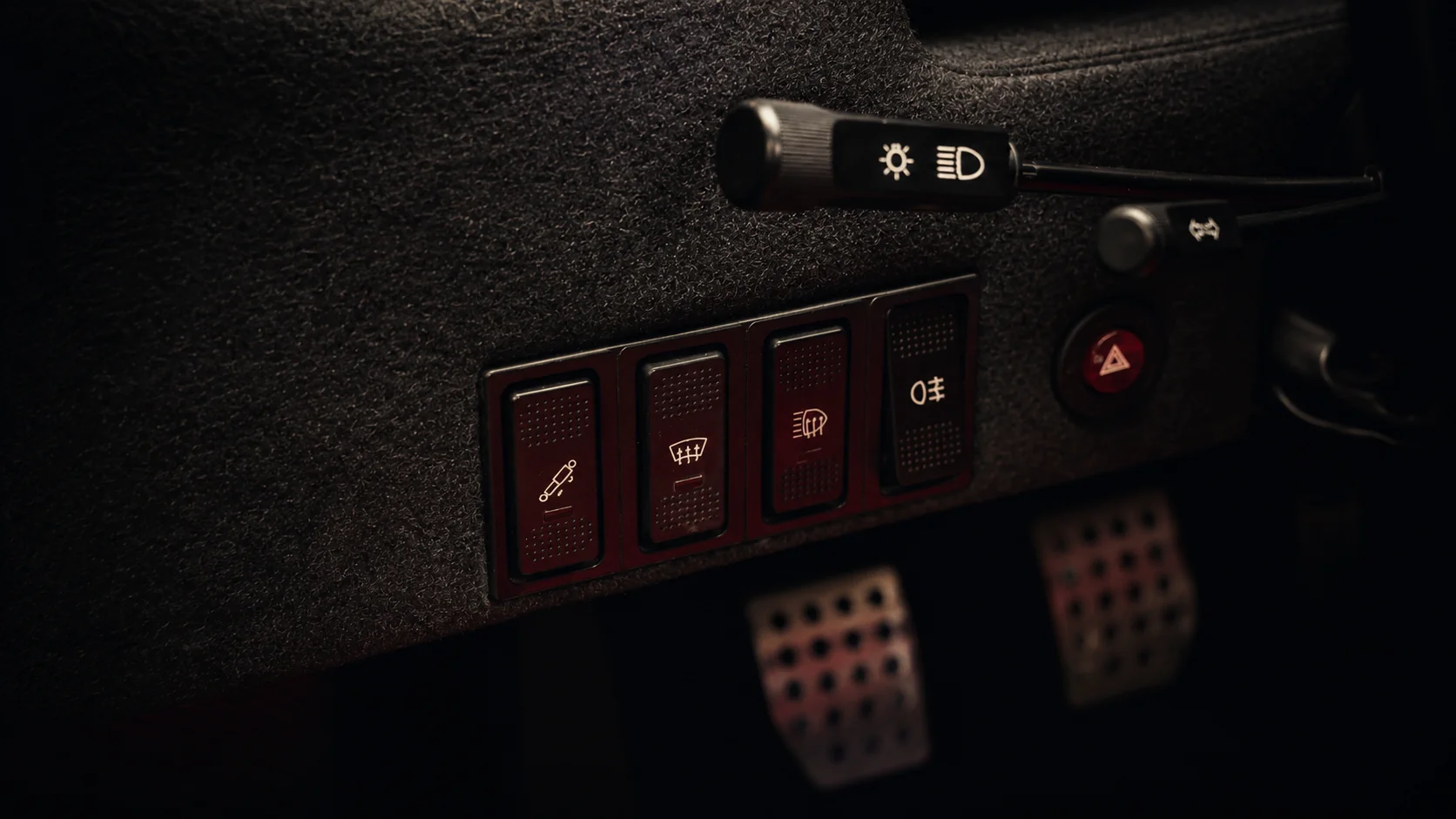 Red rocker switches and column stalks on the grey felt dashboard of a Ferrari F40