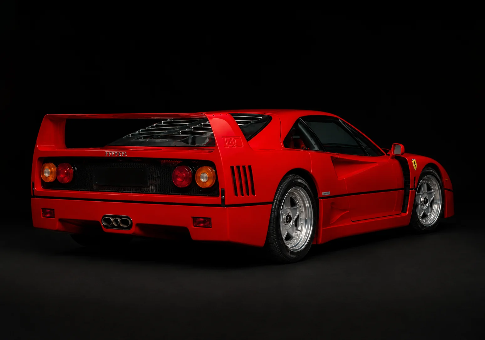 The front three-quarter of a red Ferrari F40 with its pop-up headlights raised